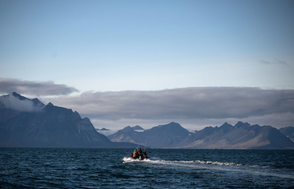 A ship sails past an island of the Svalbard archipelago, Norway