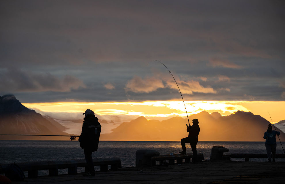 Men fish at night in the settlement of Barentsburg on the Svalbard archipelago