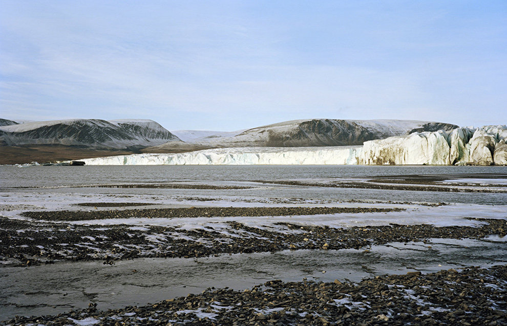 A wide, flat beach is left behind a melting glacier, which has receded over years