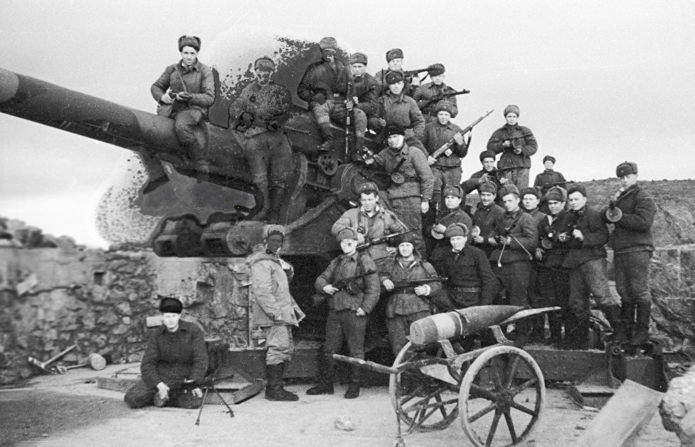 Советские солдаты сидят на немецкой пушке, захваченной в ходе боёв