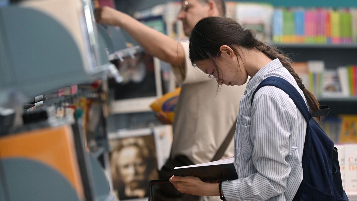 Девушка выбирает книгу в книжном магазине