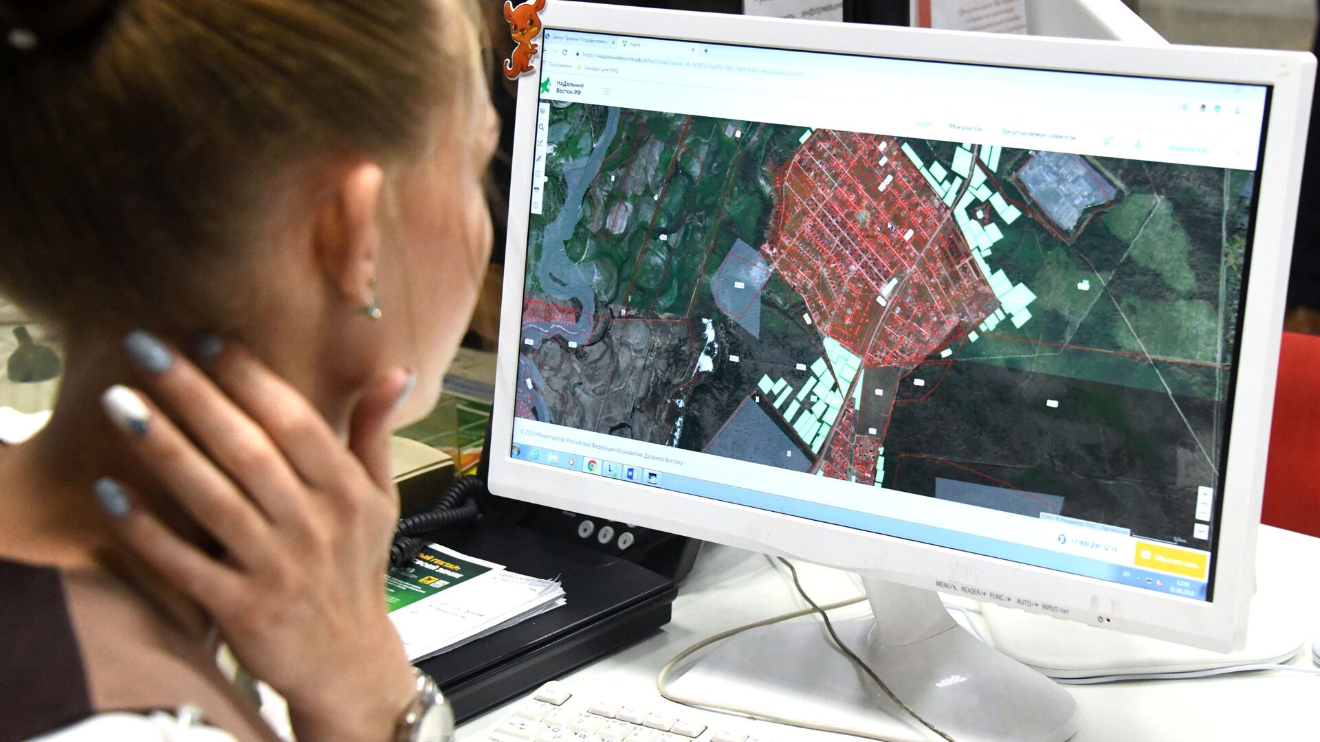 Девушка выбирает участок земли в Центре государственных и муниципальных услуг - РИА Новости, 1920, 23.01.2026